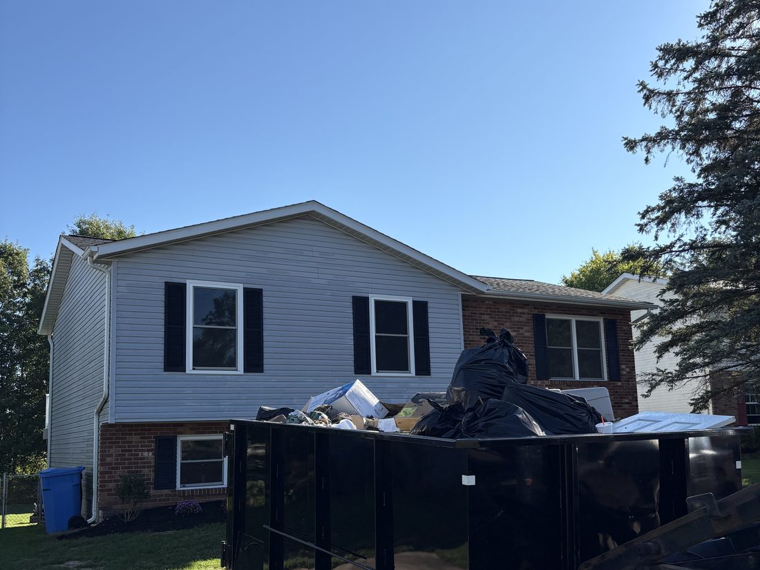 Dumpster filled for a residential cleanout next to a two-story home