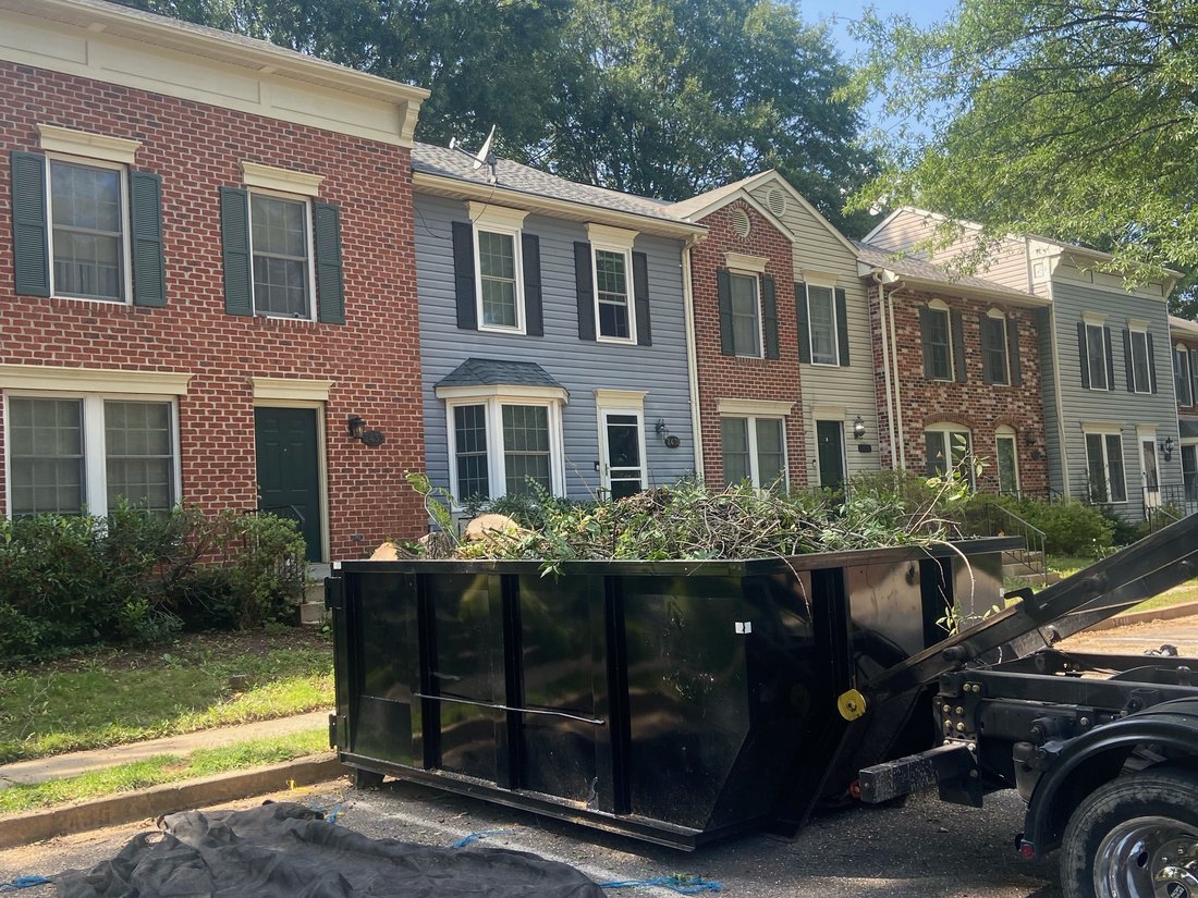 Dumpster filled with yard waste and tree branches in a townhome community