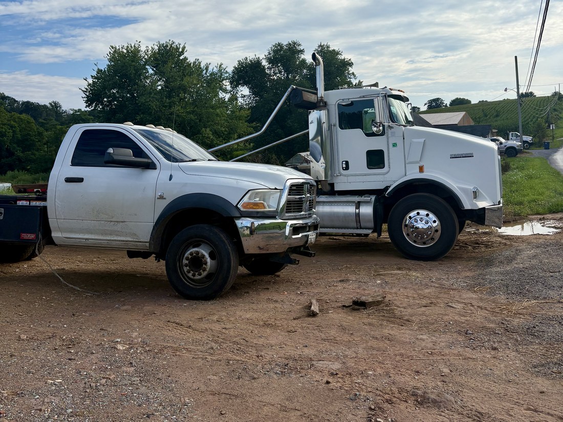 Two Savage's Waste Solutions trucks parked side by side on a farm property